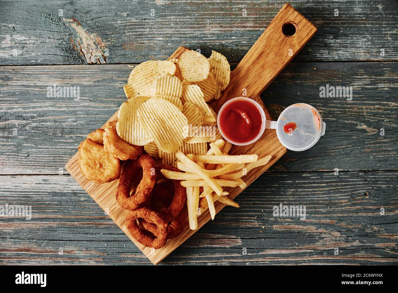 Cibo malsano e spazzatura. Diversi tipi di fastfood e snack sul tavolo, primo piano. Cibo da asporto Foto Stock