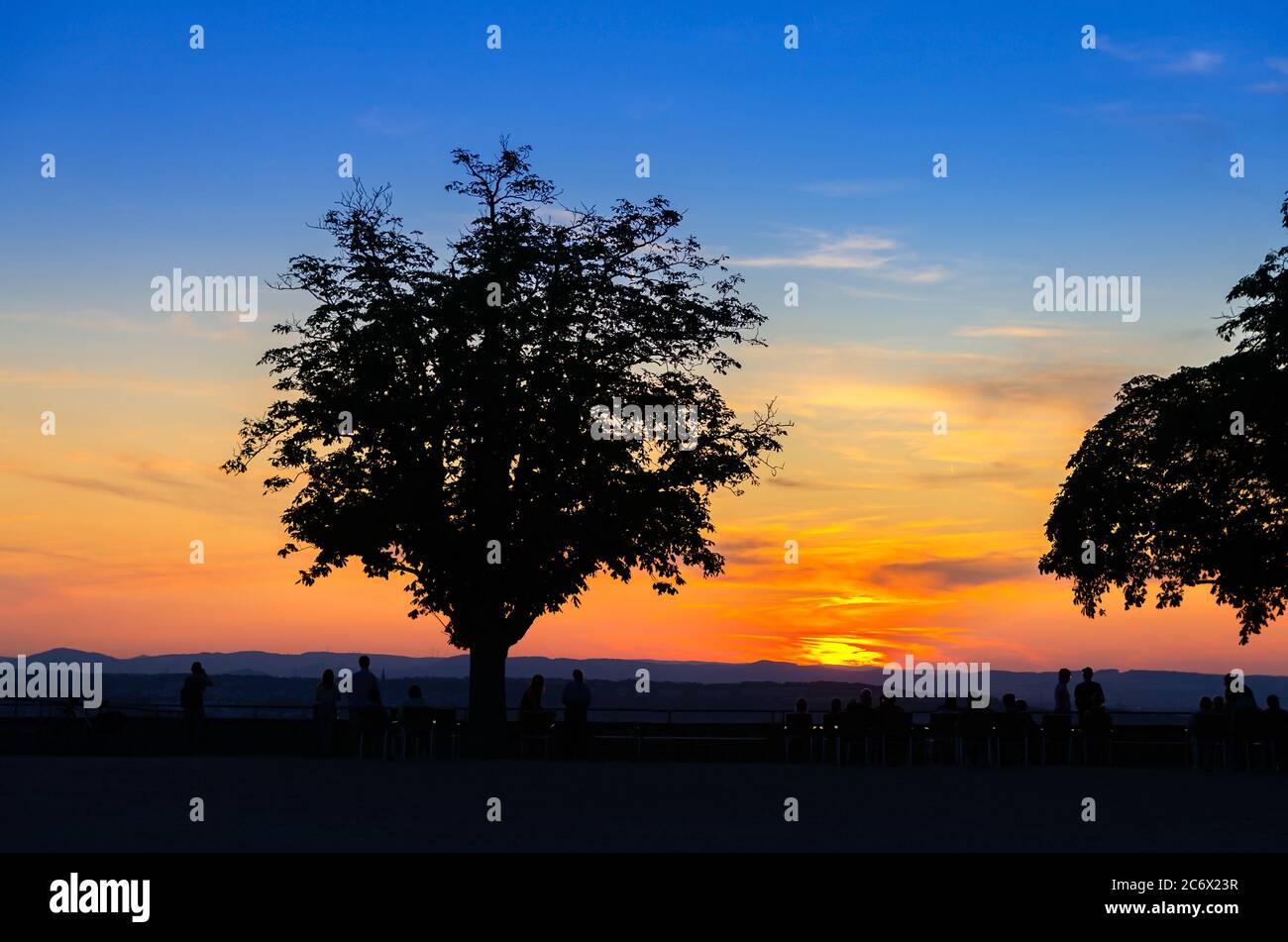 Silhouette di alberi e persone che guardano a incredibili colorati tramonto rosso all'orizzonte, vista al crepuscolo serale Foto Stock