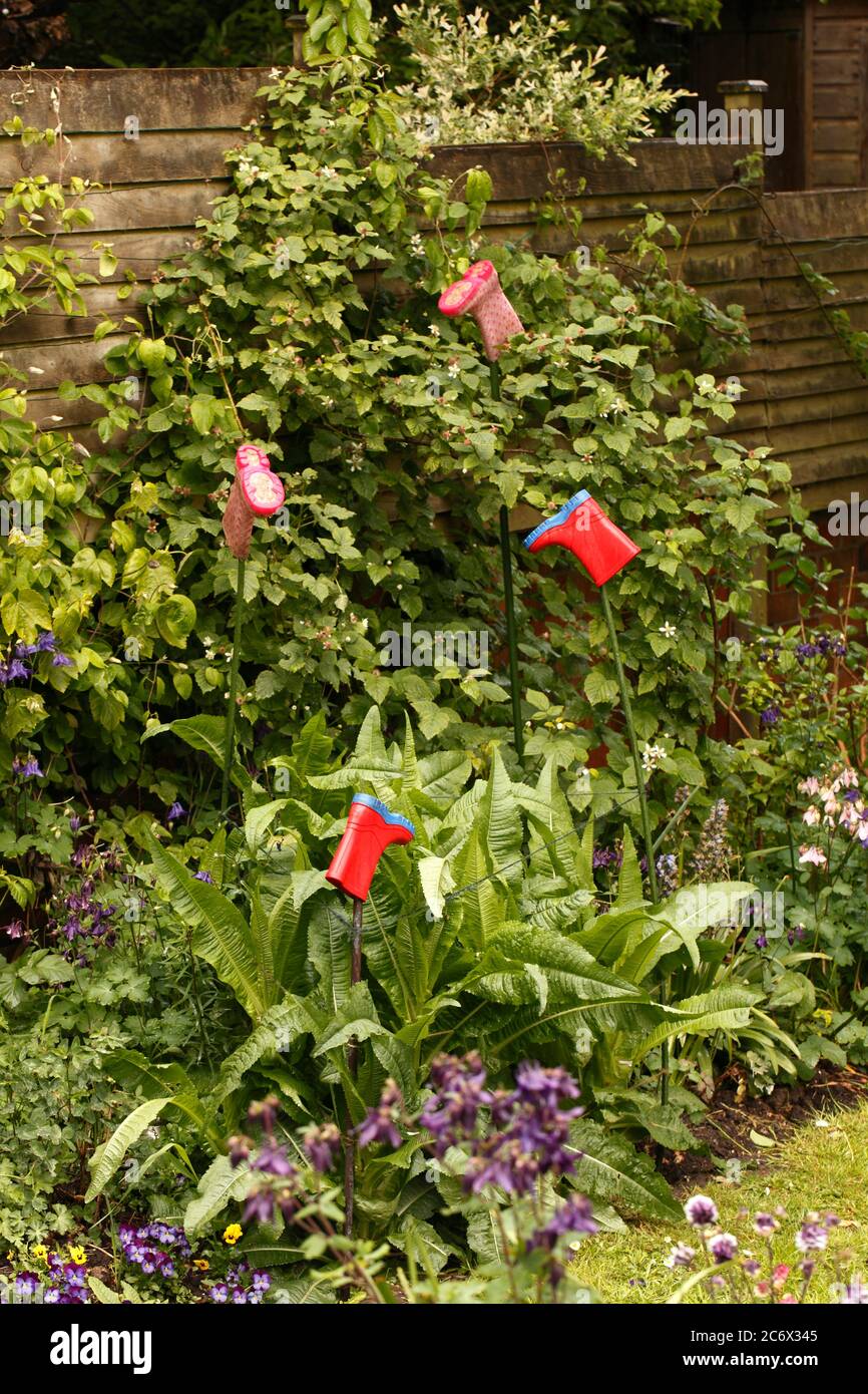 Colorati stivali wellington per bambini utilizzati in giardino come paletti o protettori o cappucci per gli occhi. Foto Stock
