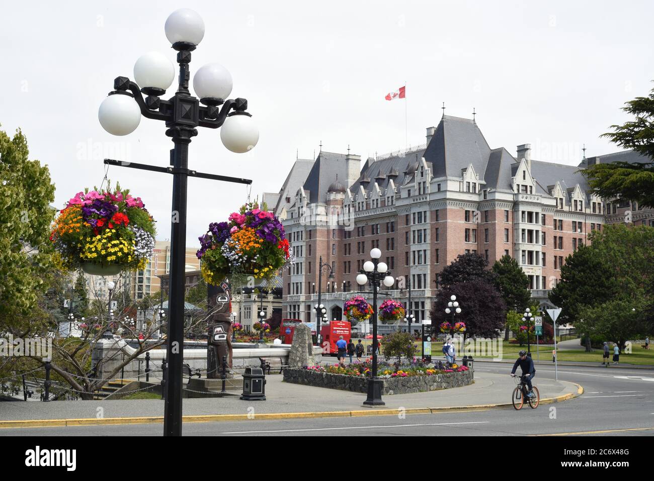 Una vista dei cestini di fiori appesi e dello storico Fairmont Empress Hotel nel centro di Victoria, Britsih Columbia, Canada sull'Isola di Vancouver. Foto Stock