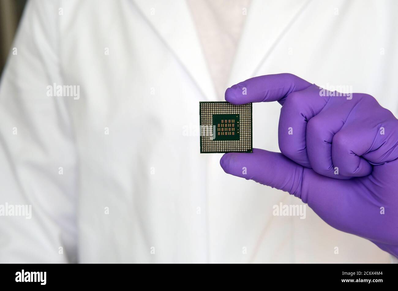 Microchip di grandi dimensioni (microprocessore) dimostrato dallo scienziato in guanti e un camice da laboratorio bianco. Spazio di copia. Foto Stock