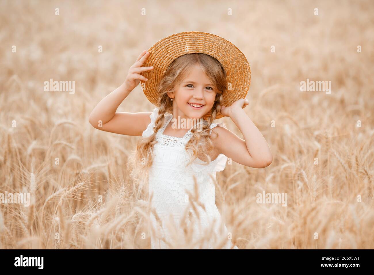 Adorabile bambina gioca su un campo di grano in una calda giornata estiva Foto Stock