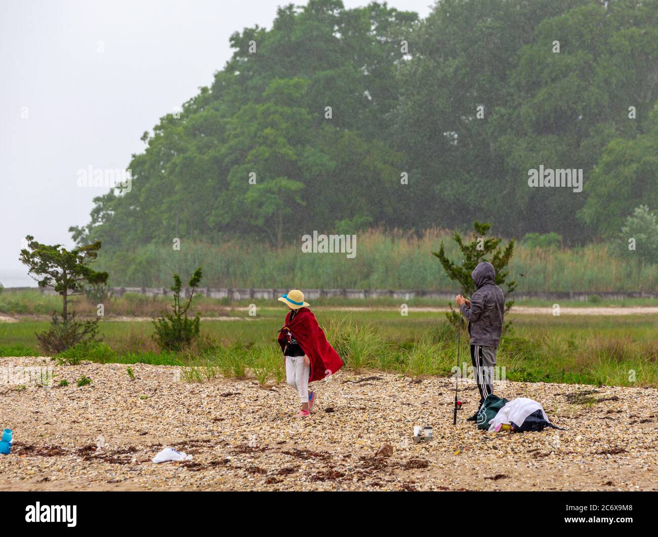 Una coppia su una spiaggia rocciosa di Shelter Island dove pescare la pioggia Foto Stock