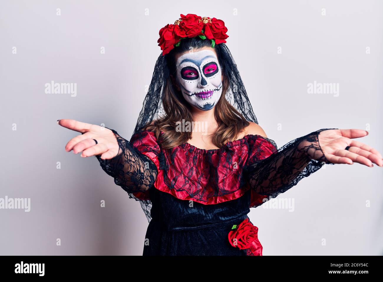 Giovane donna che indossa giorno del costume morto su bianco guardando la macchina fotografica sorridente con le braccia aperte per abbraccio. Espressione allegra abbracciando la felicità. Foto Stock