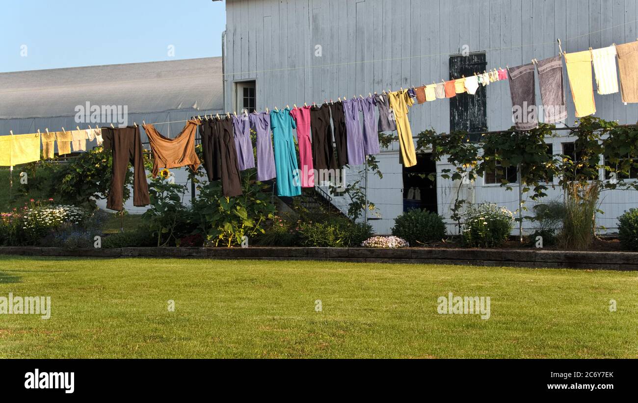 Una linea di abbigliamento con colorati abiti Amish fatti a mano, appesi ad asciugare alla luce del sole del mattino Foto Stock