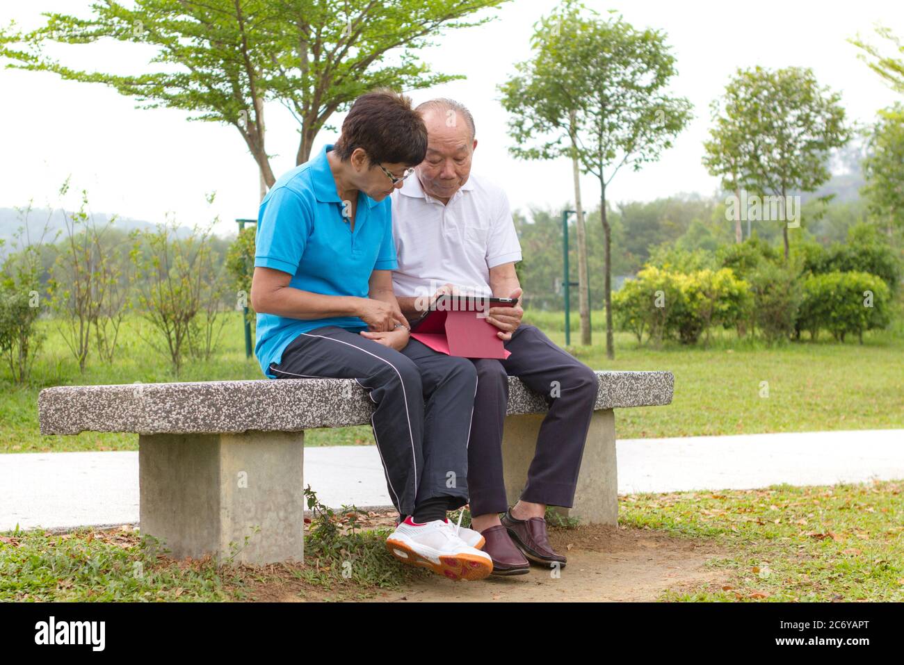 Anziana coppia cinese che guarda il tablet mobile. Stile di vita digitale. Foto Stock