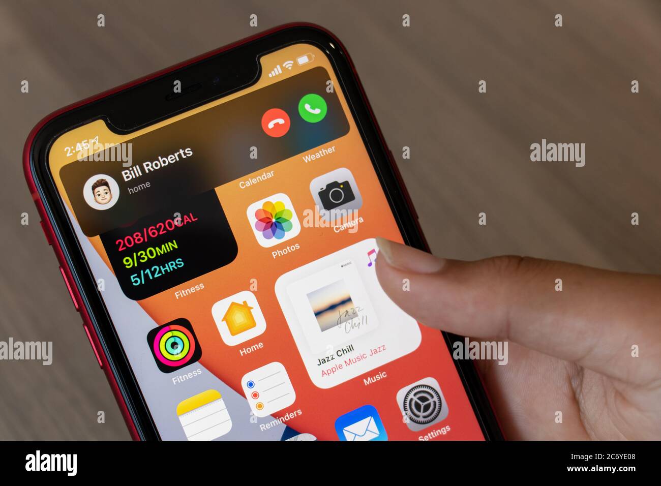 Persona che riceve una chiamata telefonica sul proprio iPhone, mentre utilizza il software operativo Apple più recente iOS 14. Che aggiunge una funzione di risposta non a schermo intero. Foto Stock