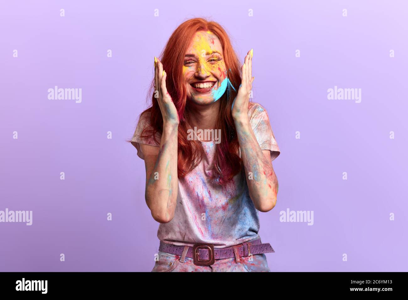 Felice ragazza con sorriso togoteo che tocca il viso, donna con braccia sollevate esprime la sua felicità dopo holli, celebrazione, compleanno Foto Stock