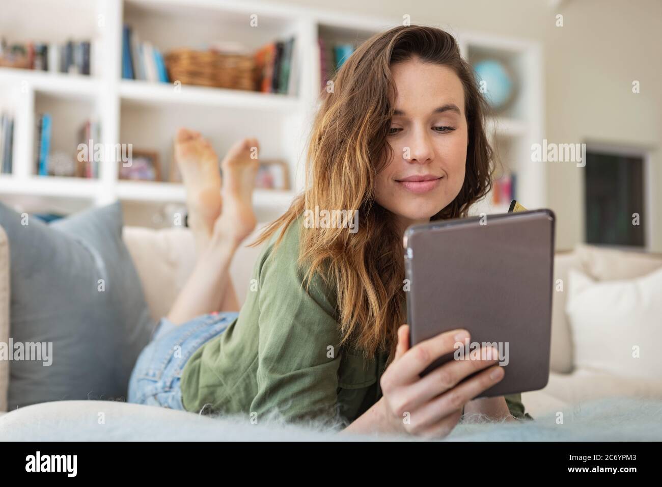 Donna con tavoletta digitale in casa Foto Stock