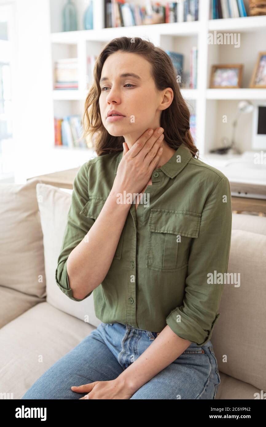 Donna con gola irritata che tiene il collo a casa Foto Stock