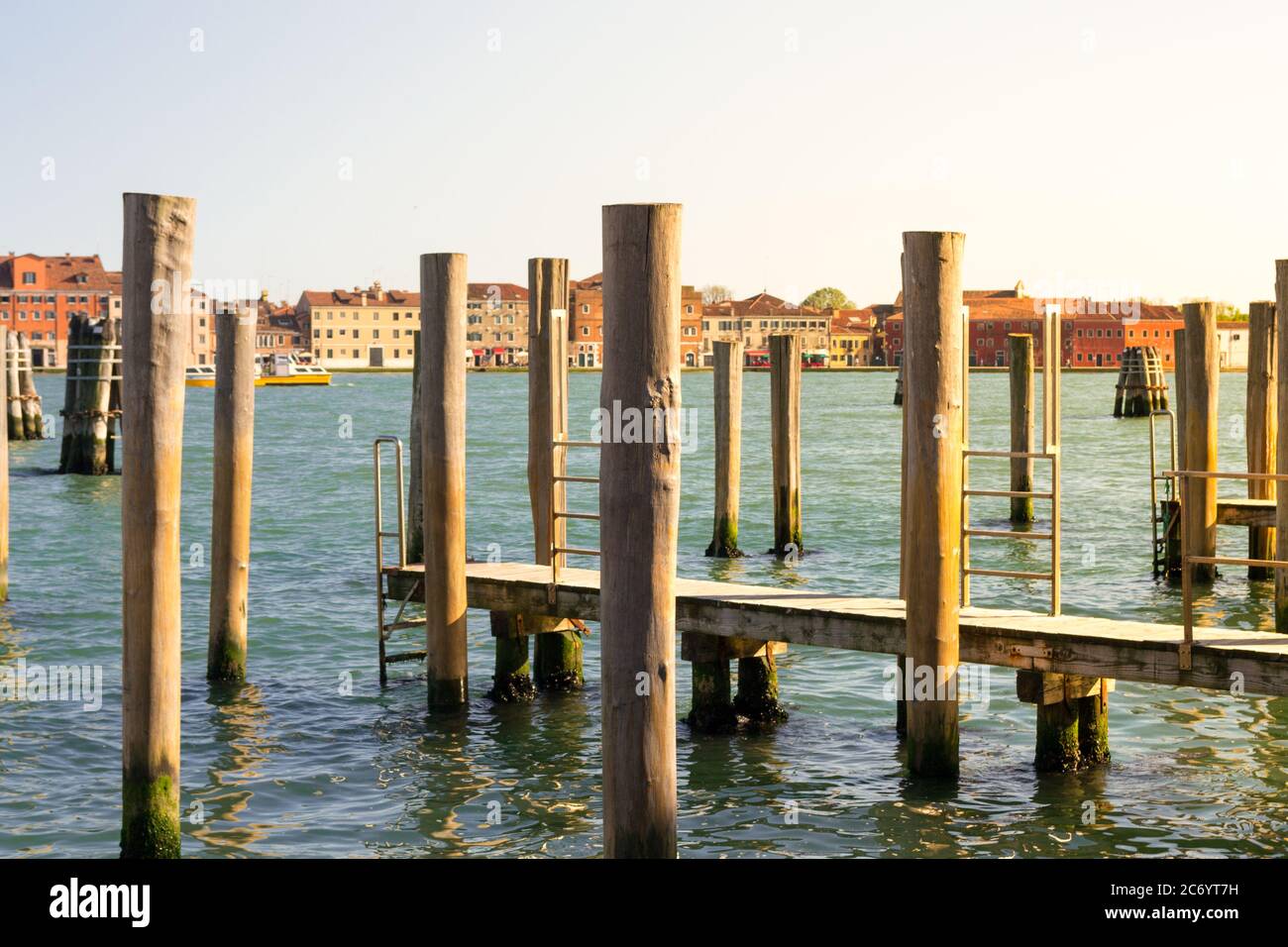 Venezia, Italia. Vista panoramica tipica della laguna, rawn di pali ormeggi in prospettiva con la peculiare architettura veneziana sullo sfondo. Foto Stock