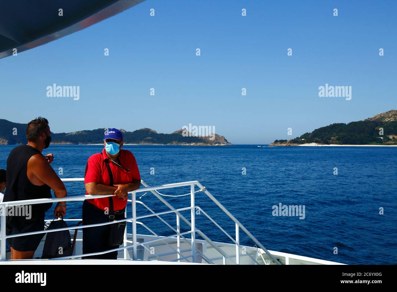 12 luglio 2020, Ria de Vigo, Galizia, Spagna settentrionale: Passeggeri che indossano maschere sul traghetto da Vigo alle Isole Cies (sullo sfondo), una popolare destinazione turistica al largo della costa della Galizia. La Spagna ha rilassato le restrizioni di viaggio dal 21 giugno dopo un rigoroso blocco per controllare il Coronavirus Covid 19 e molti spagnoli stanno tornando alle spiagge. L'uso di maschere facciali è ancora obbligatorio sui trasporti pubblici. Foto Stock