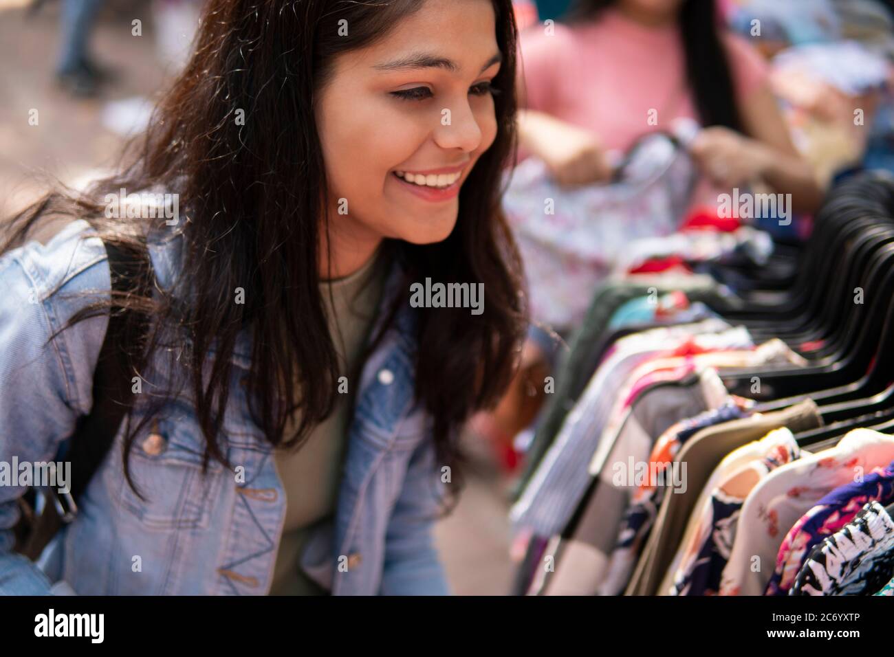 Felice ragazza teen in ritardo cercando e acquistare vestiti dal mercato di strada all'aperto di Delhi, India al giorno. Sparare luogo Sarojini Nagar, Delhi, India. Foto Stock