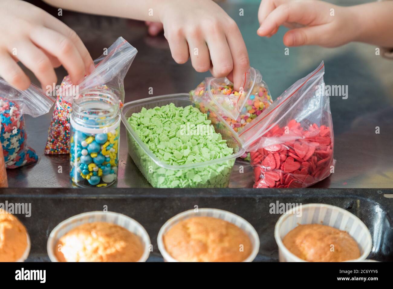 I bambini decorano i cupcake di spugna di blank con la pasta colorata Foto Stock