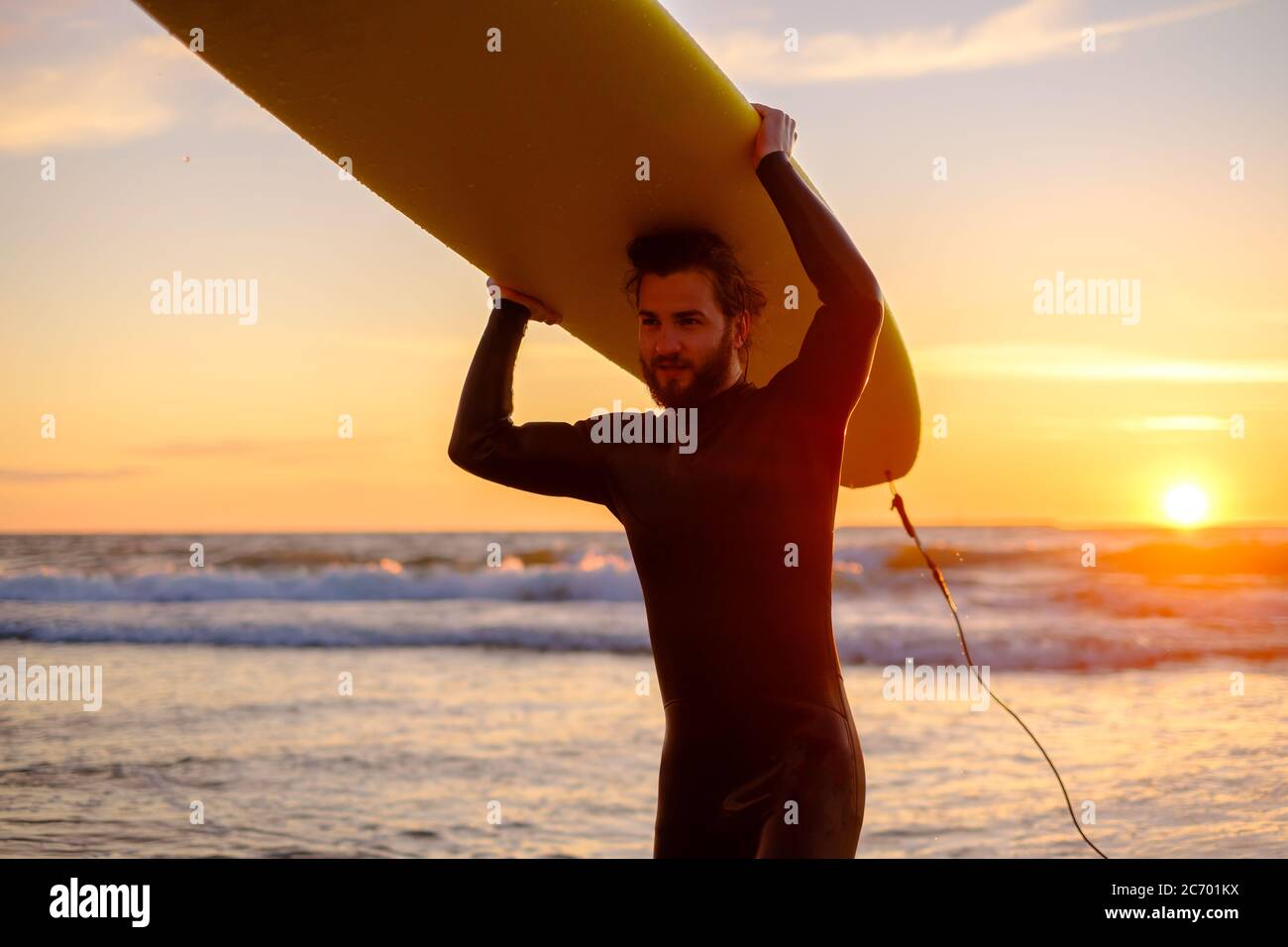 Surfista forte bearded nel tramonto Foto Stock