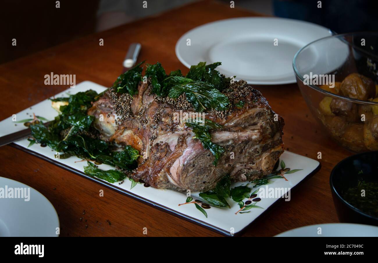 Gamba di agnello cotta in casa (cucinata sous vide), decorata con semi di menta e senape su un tavolo di legno. DOF. Bassa Foto Stock
