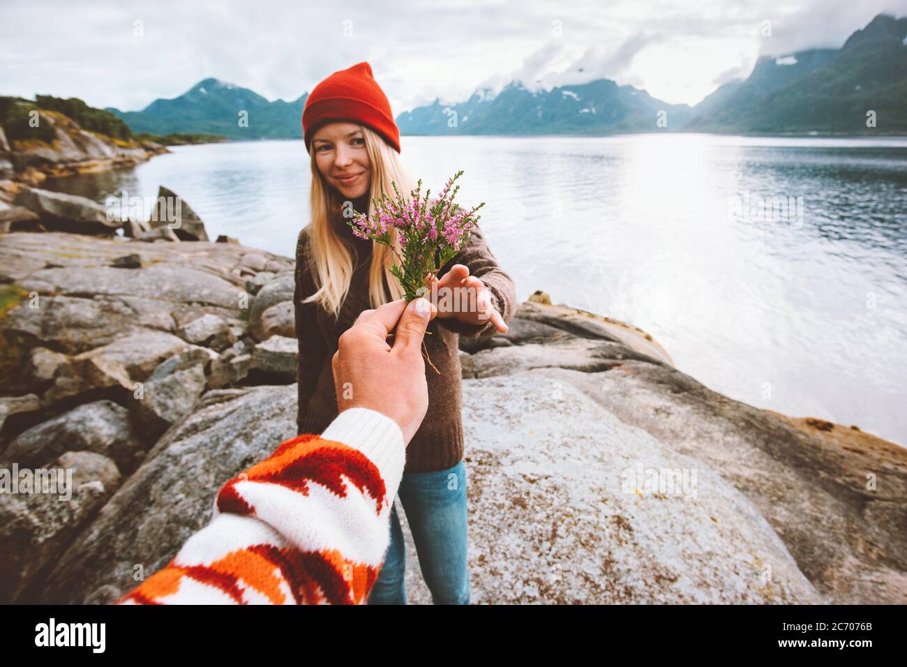 Romantico dono mano che dà fiori bouquet a ragazza coppia in amore vacanza all'aperto giovane donna con berretto rosso Foto Stock