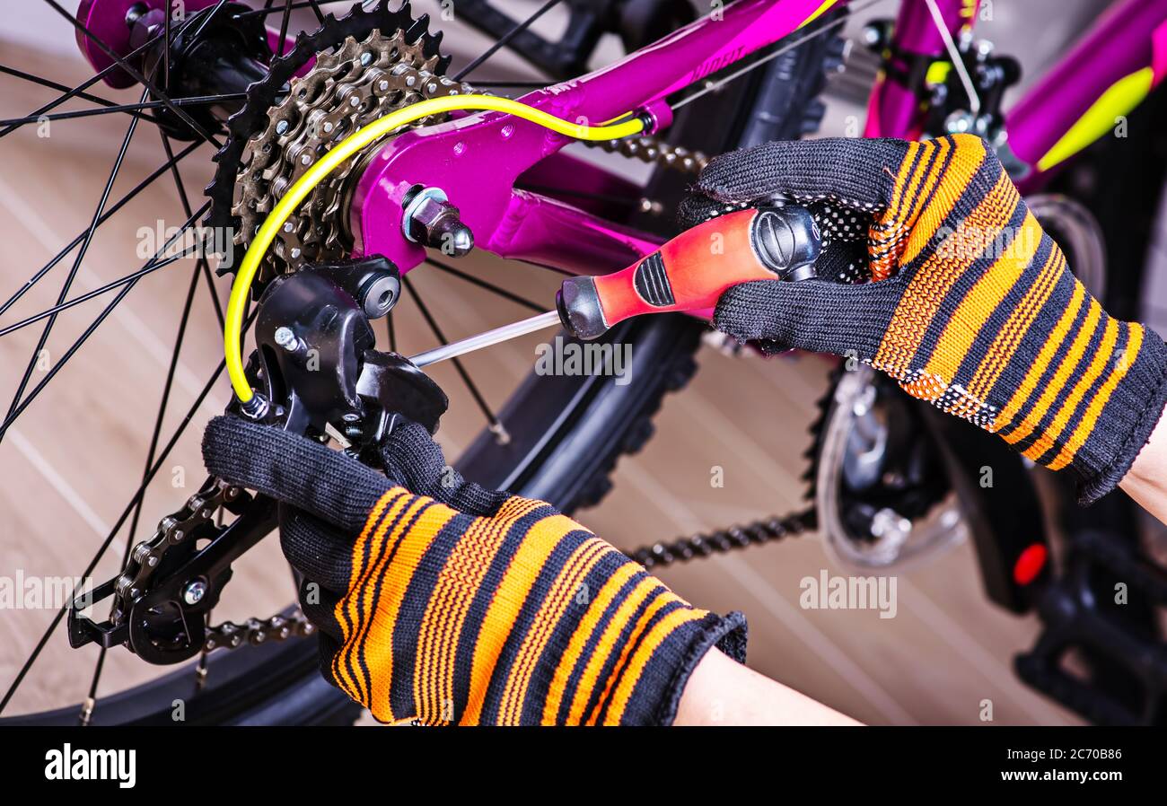 Addetto alla manutenzione meccanico addetto alla riparazione durante l'installazione dell'assemblaggio o della regolazione dell'ingranaggio della bicicletta. Foto Stock