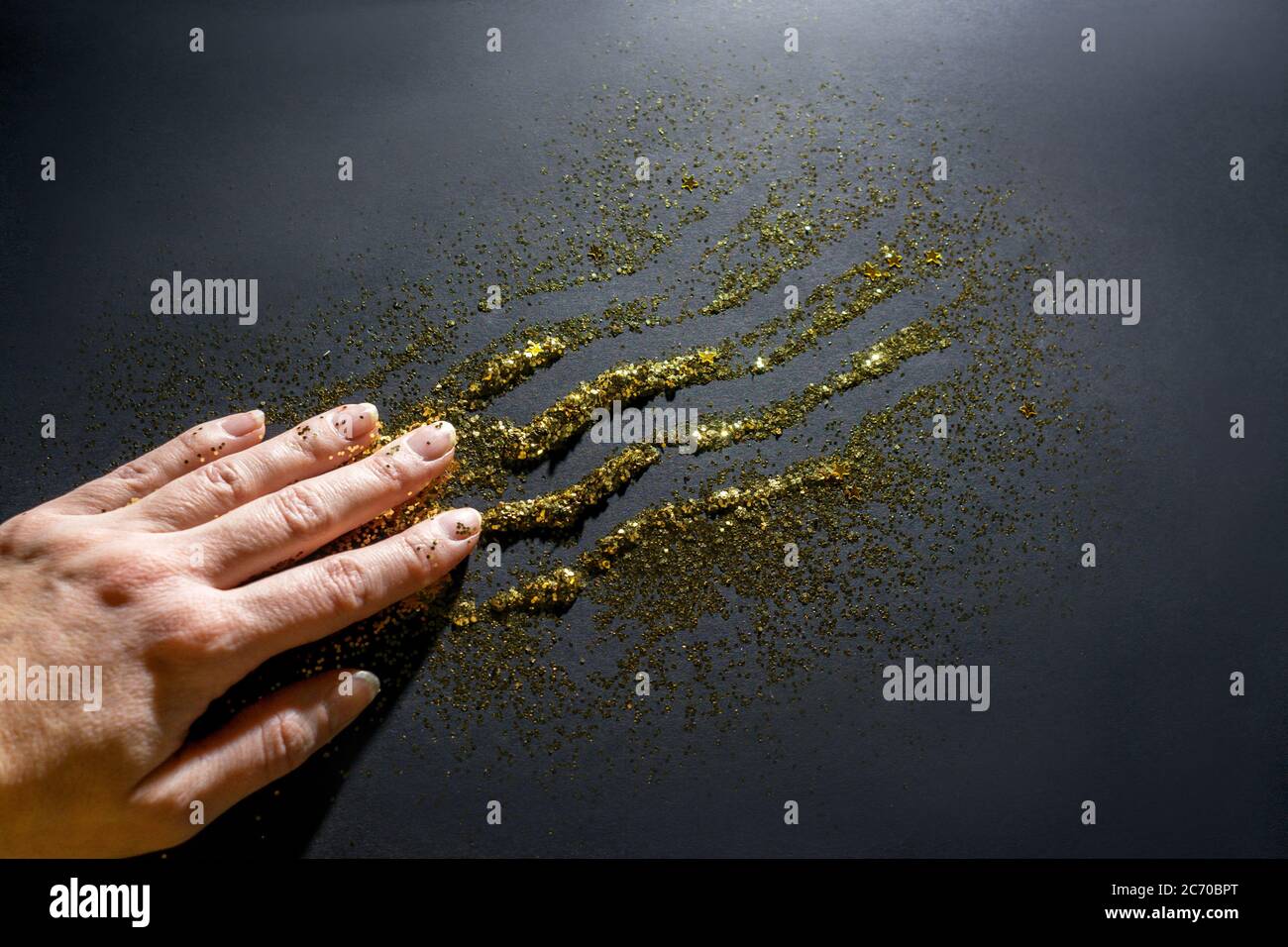 La mano conduce lungo le scintille e lascia un segno. Scintille scintille. Sfondo nero. Foto Stock