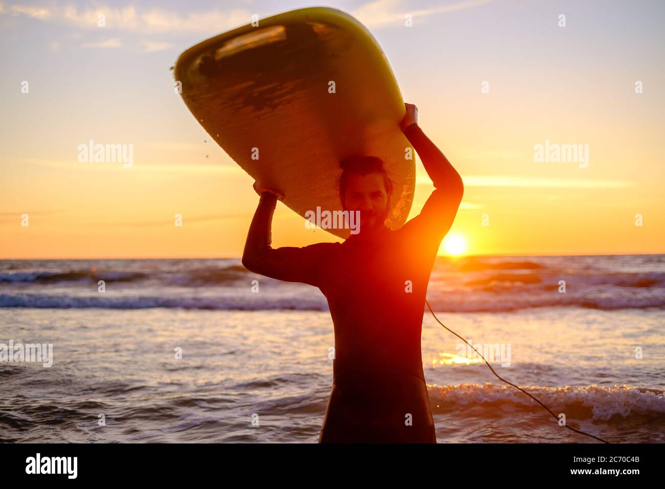 Surfer con portento felice al tramonto Foto Stock