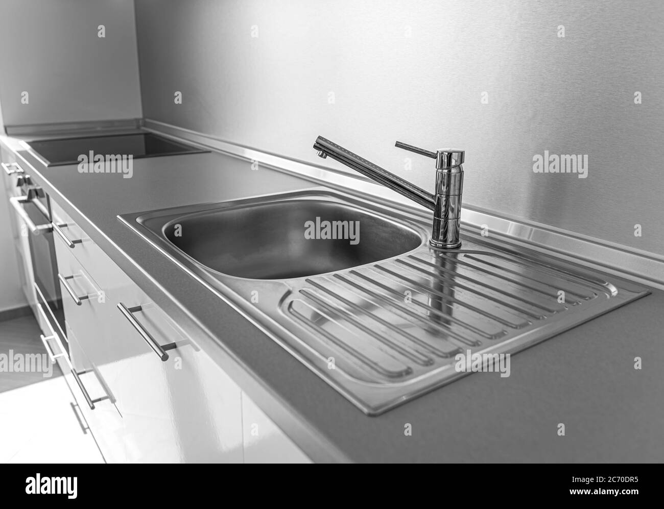 Lavello e rubinetto in cucina su un piano di lavoro. Foto Stock