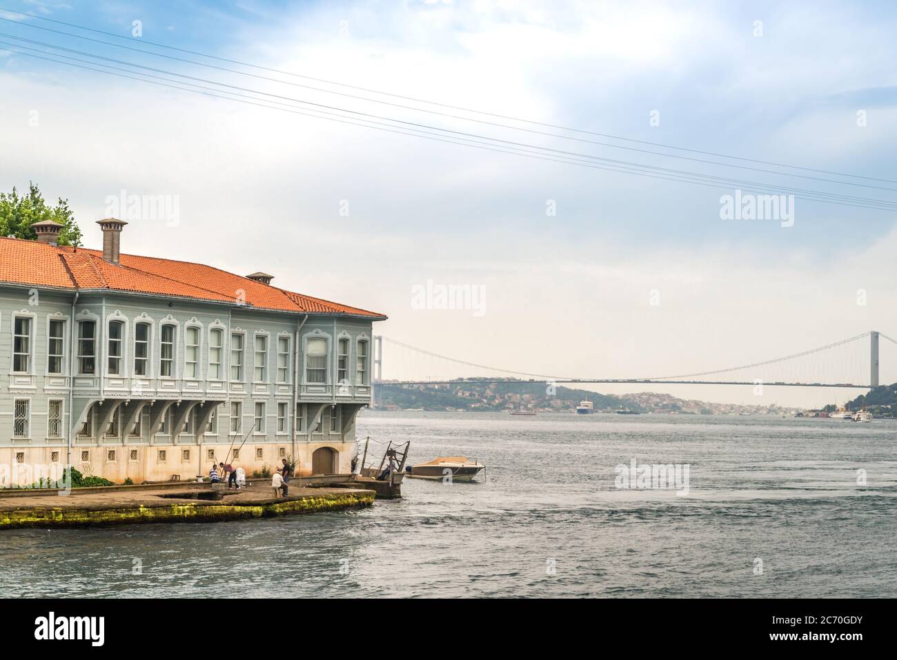 Una scena a Istanbul, in Turchia, che mostra un gruppo di uomini che pescano dalla riva, e un moderno ponte che attraversa lo stretto del Bosforo sullo sfondo Foto Stock