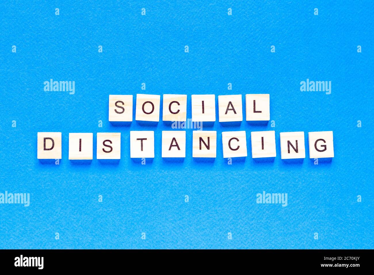 Parole di distanza sociale. Iscrizione in legno su sfondo blu. Segno di informazione di distanza sociale da blocchi su sfondo blu. Vista dall'alto, fl Foto Stock