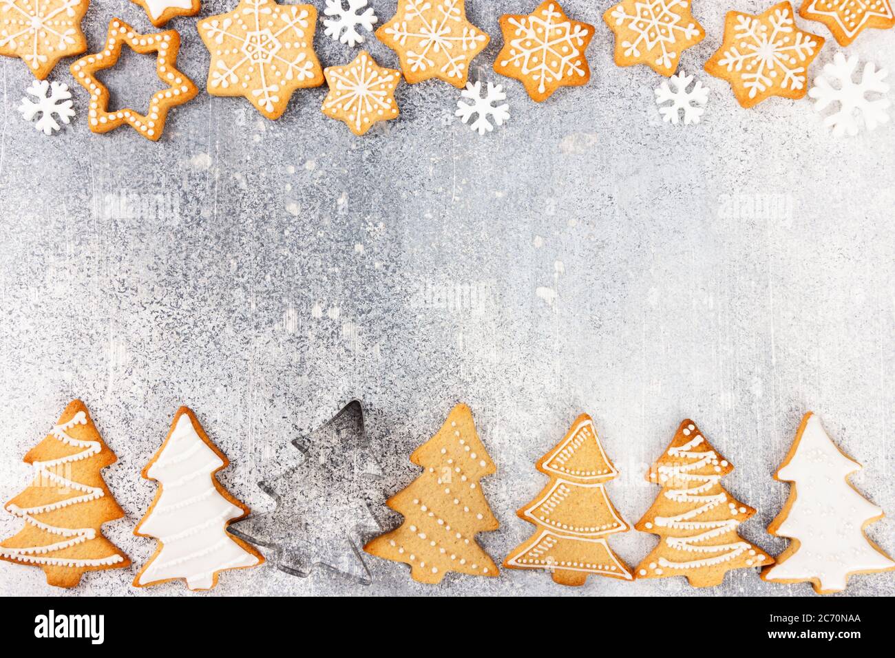 Modello di Natale di biscotti di pan di zenzero a forma di albero di Natale e fiocchi di neve su sfondo grigio chiaro di pietra. Vista dall'alto. Foto Stock