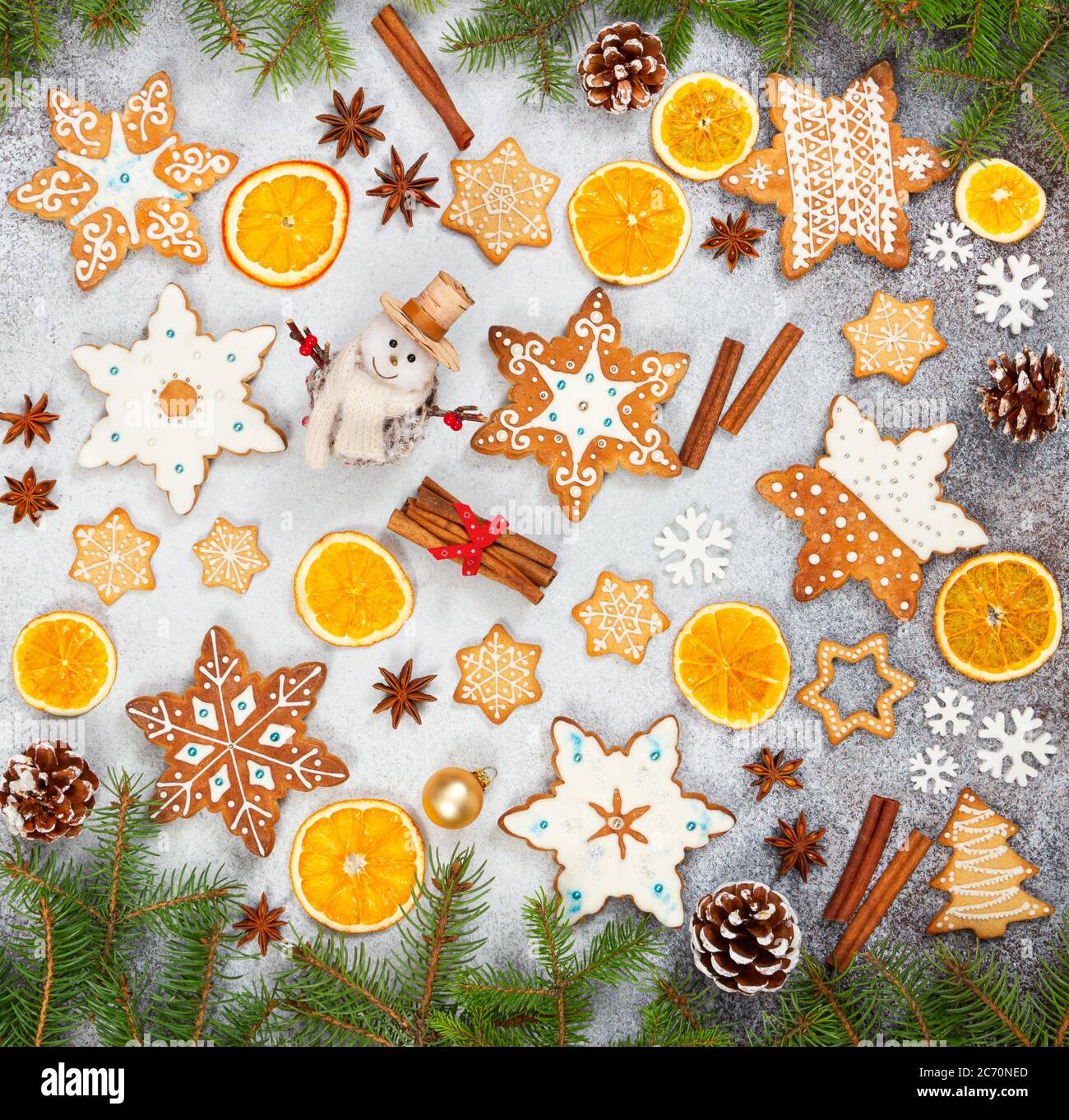 Biscotti allo zenzero natalizio in forma di fiocchi di neve, arancio secco, anice stellato e pupazzo di neve su fondo di pietra grigia. Vista dall'alto. Simboli di Capodanno e Chr Foto Stock
