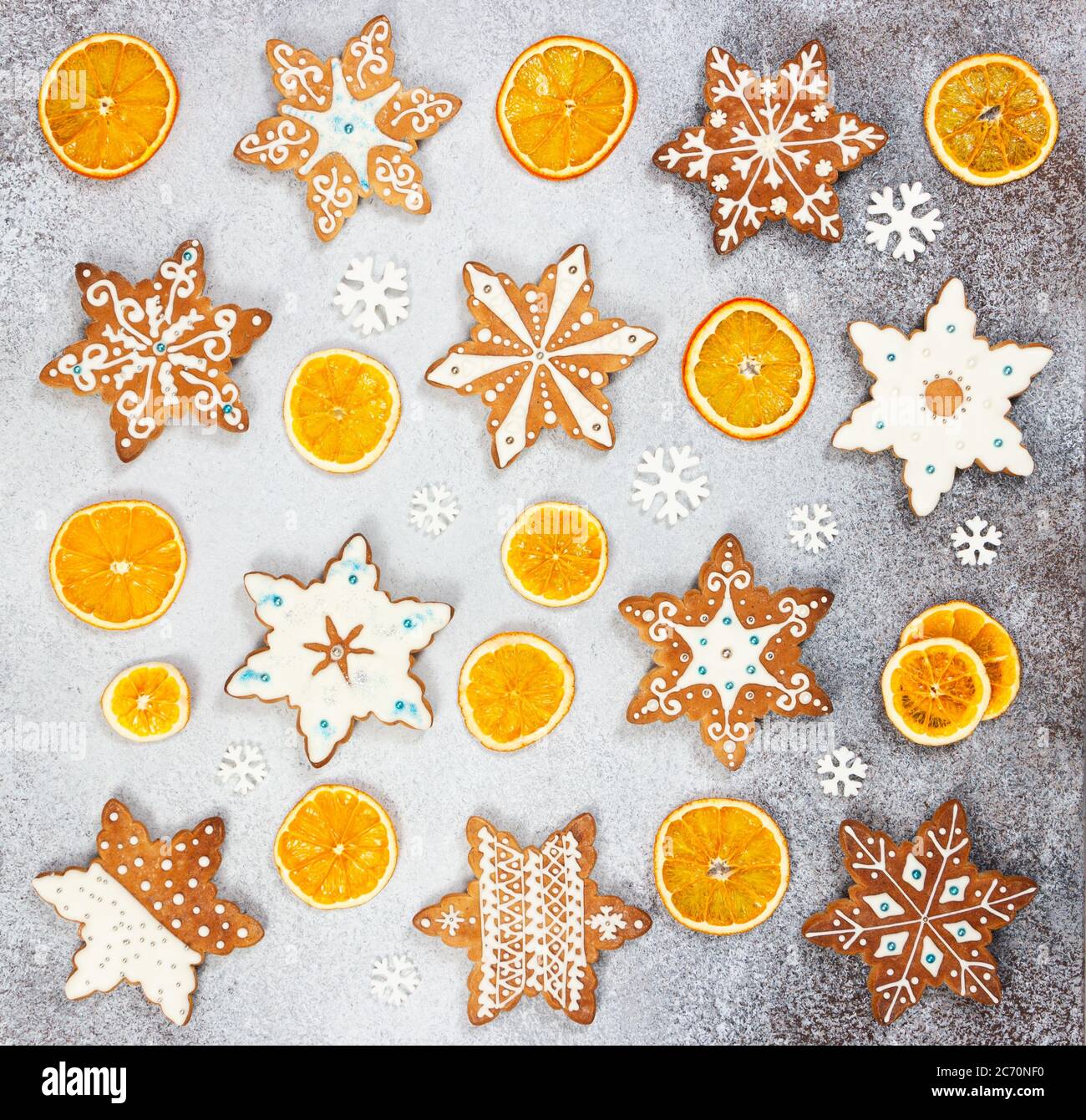 Biscotti allo zenzero natalizio in forma di fiocchi di neve e arancio secco su fondo di pietra grigio chiaro. Vista dall'alto. Foto Stock