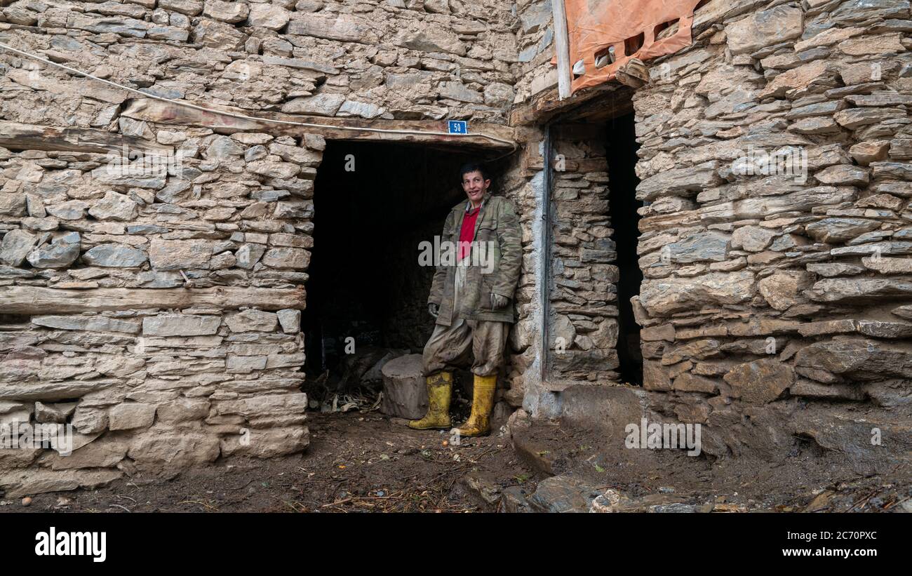 Hizan, Bitlis, Turchia - Febbraio 2020: Giovane uomo che stala da una casa di pietra, nella provincia di Hizan, un villaggio remoto nella Turchia orientale Foto Stock