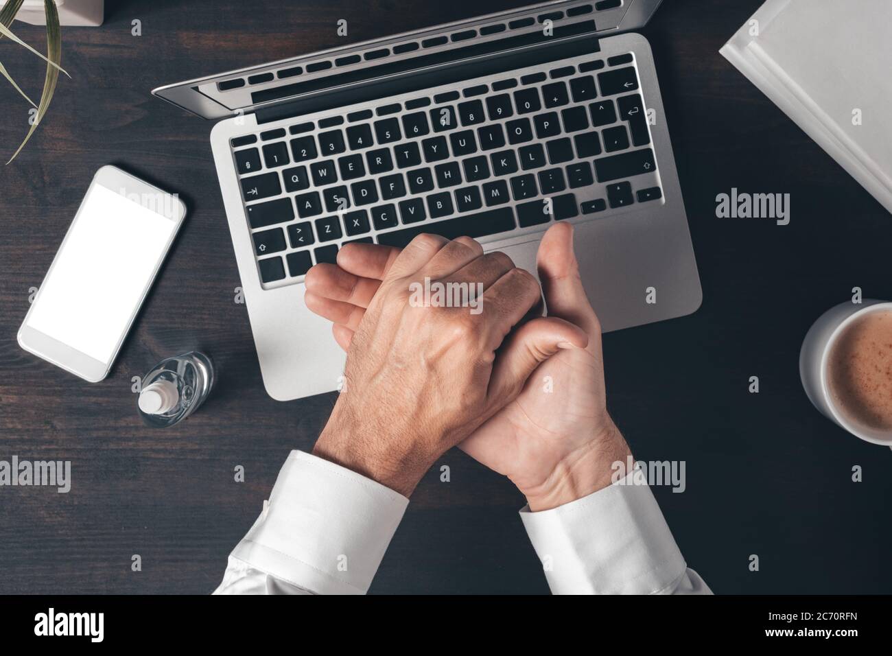 Uomo d'affari che disinfetta le mani mentre lavora scrivania da ufficio, vista dall'alto Foto Stock