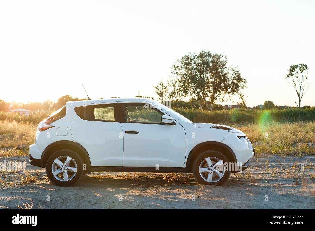 Novoselivka, regione di Dnipropetrovsk, Ucraina - 02 luglio 2020: Nissan Juke 2019 colore bianco vicino alla strada rurale al tramonto Foto Stock