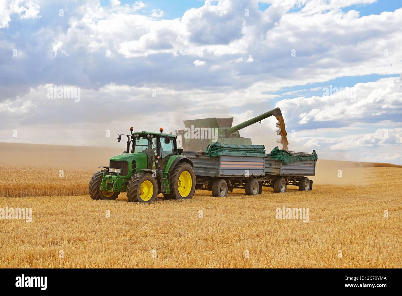 mietitrebbia e trattore nel campo dei cereali durante la mietitura estiva Foto Stock