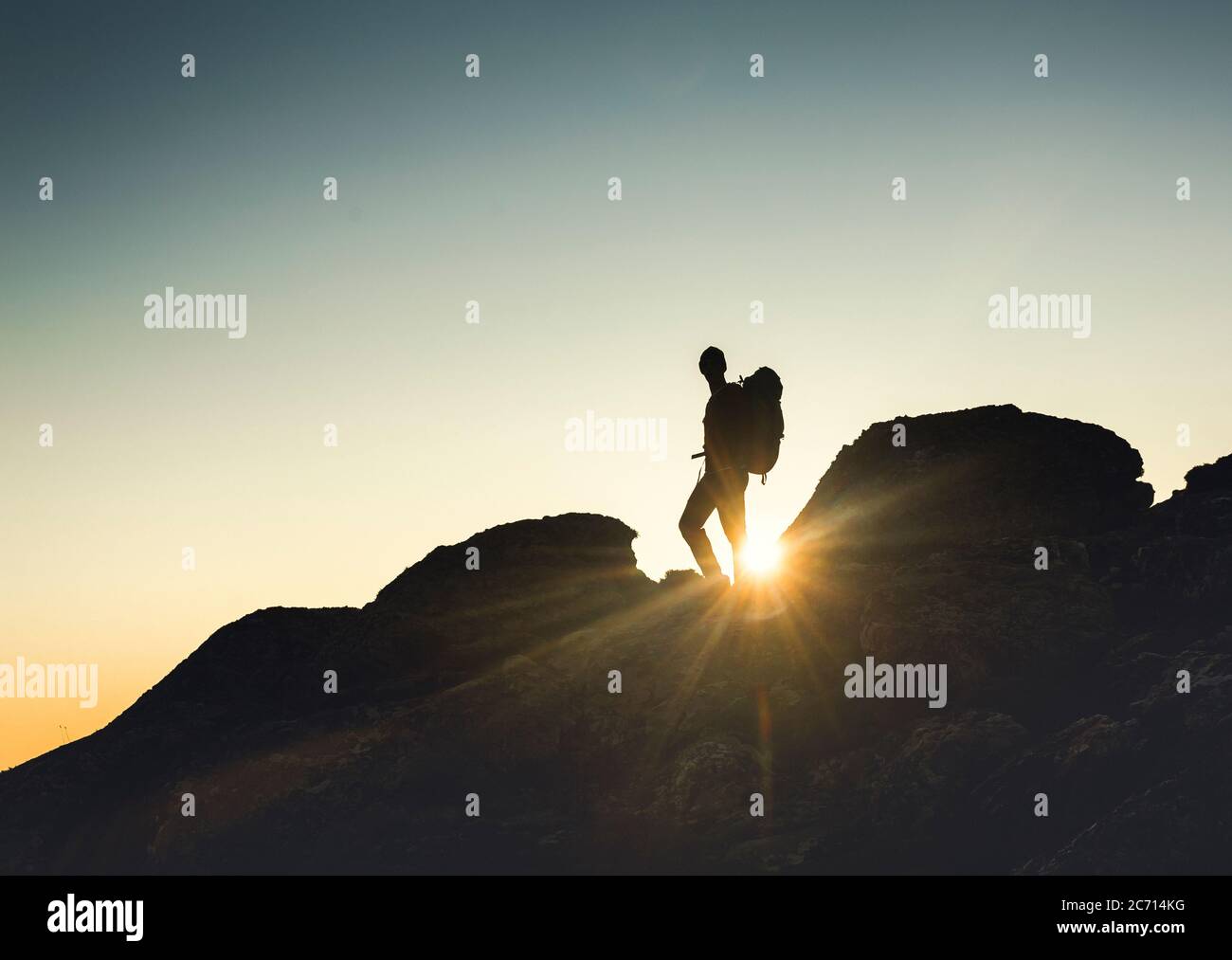 Inquadratura di un uomo a camminare sopra le montagne al tramonto Foto Stock