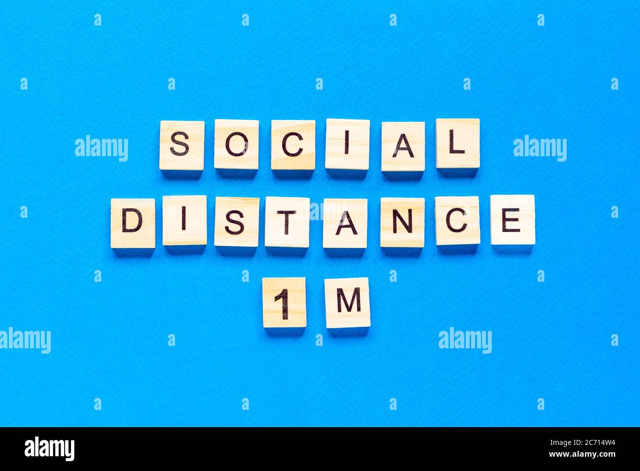 Parole distanza sociale 1 m. Iscrizione in legno su sfondo blu. Informazioni segno di distanza sociale 1 m da blocchi su sfondo blu. Vista dall'alto Foto Stock