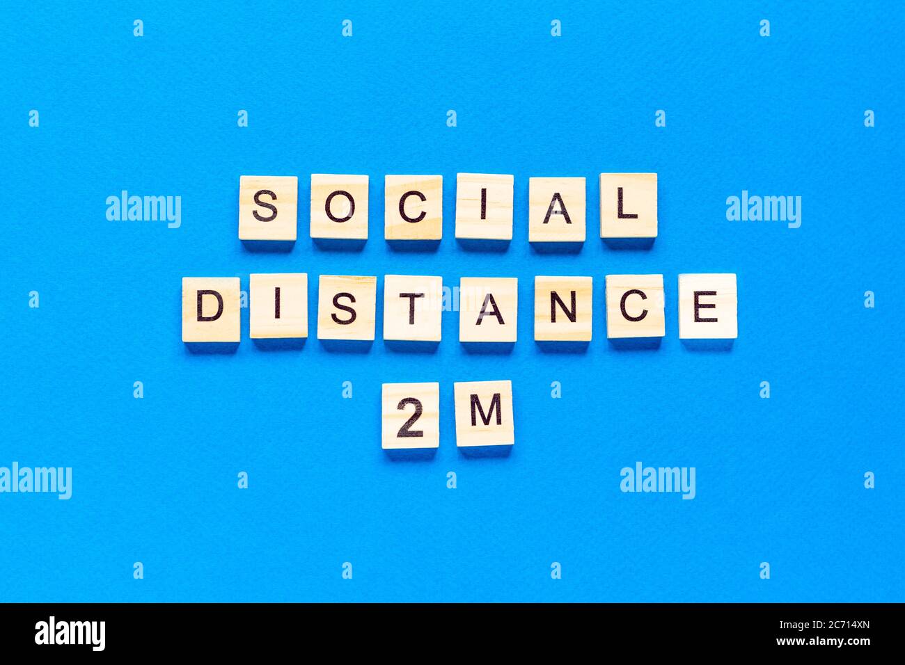 Parole distanza sociale 2 m. Iscrizione in legno su sfondo blu. Informazioni segno di distanza sociale 2 m da blocchi su sfondo blu. Vista dall'alto Foto Stock