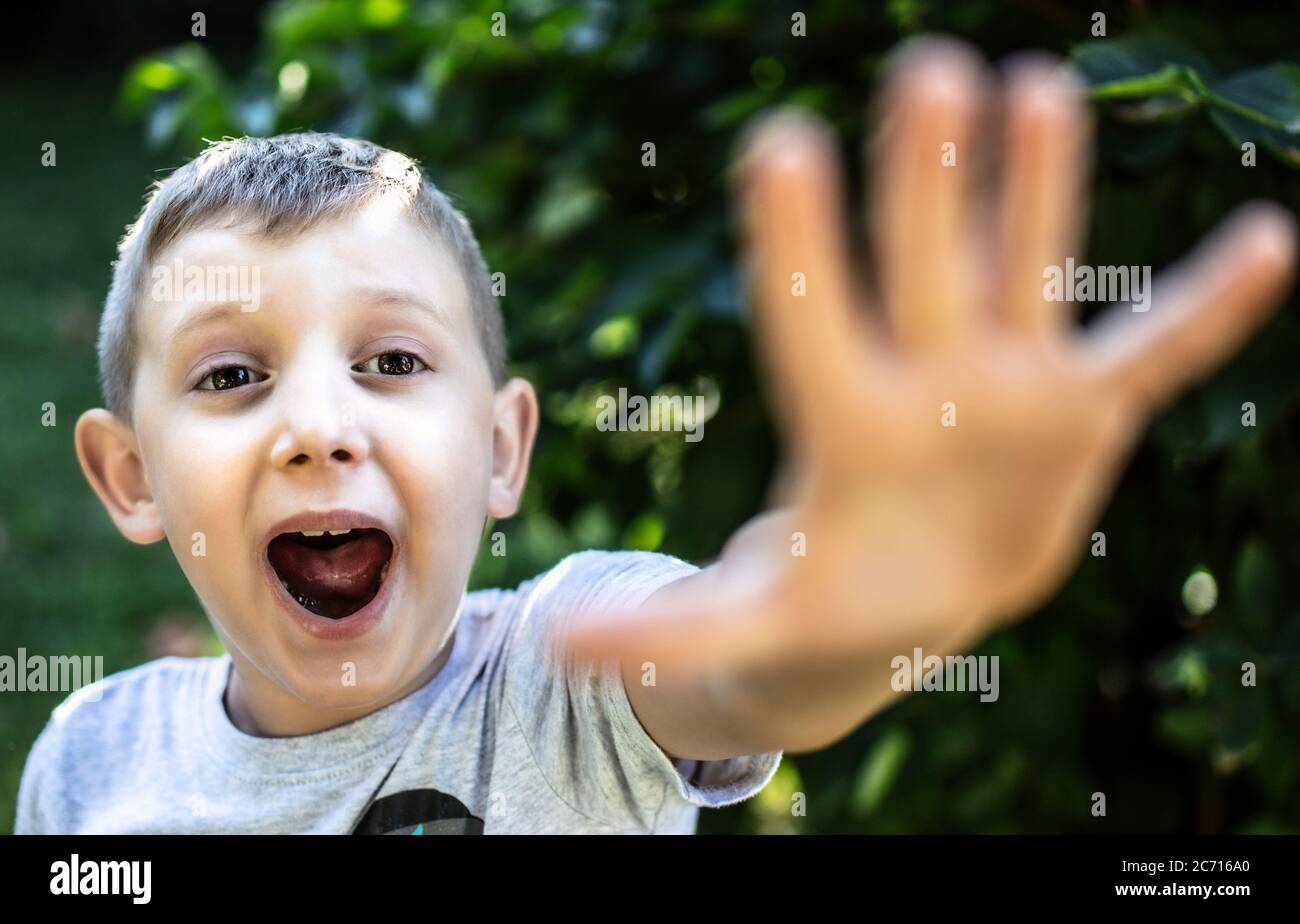 un bambino spaventato urlando e con la mano aperta verso la fotocamera. Foto Stock
