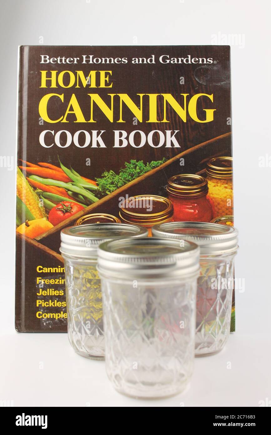 Libro di cuoco domestico inscatolante e tre vasetti isolati di muratore di vetro su uno sfondo bianco Foto Stock