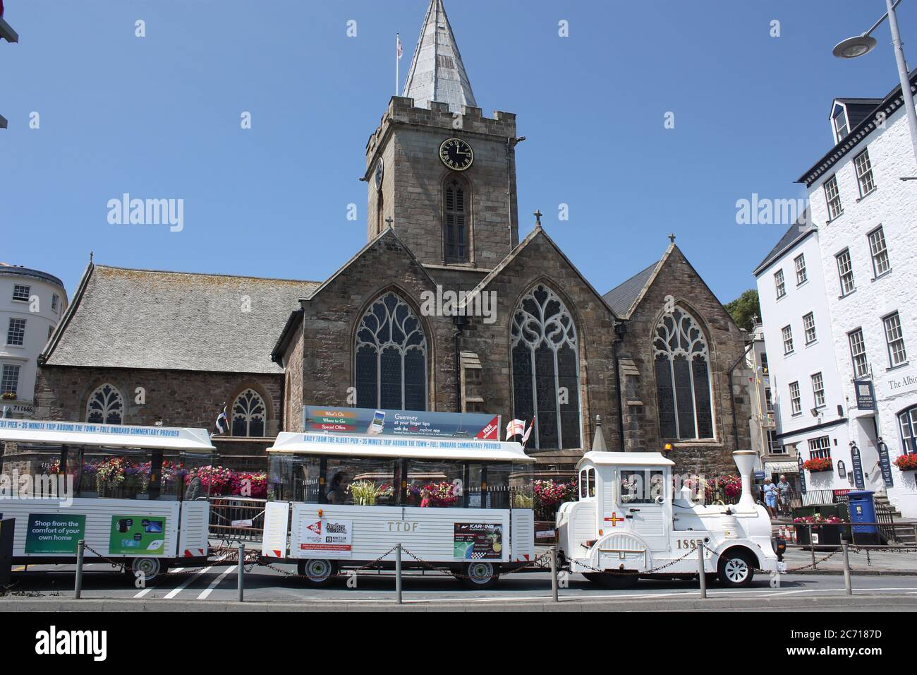 Isole del canale. Guernsey. Porto di San Pietro. Chiesa cittadina con passaggio turistico in treno. Foto Stock