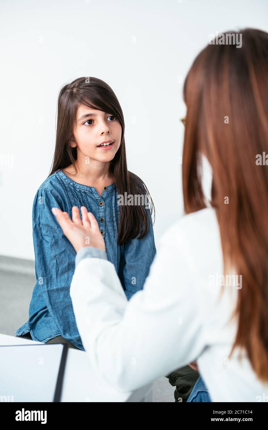 Medico psicoterapeuta, terapeuta o pediatra in camice bianco ascolta la ragazza teen durante la ricezione in clinica. Teen problemi, sessione di terapia. Foto Stock