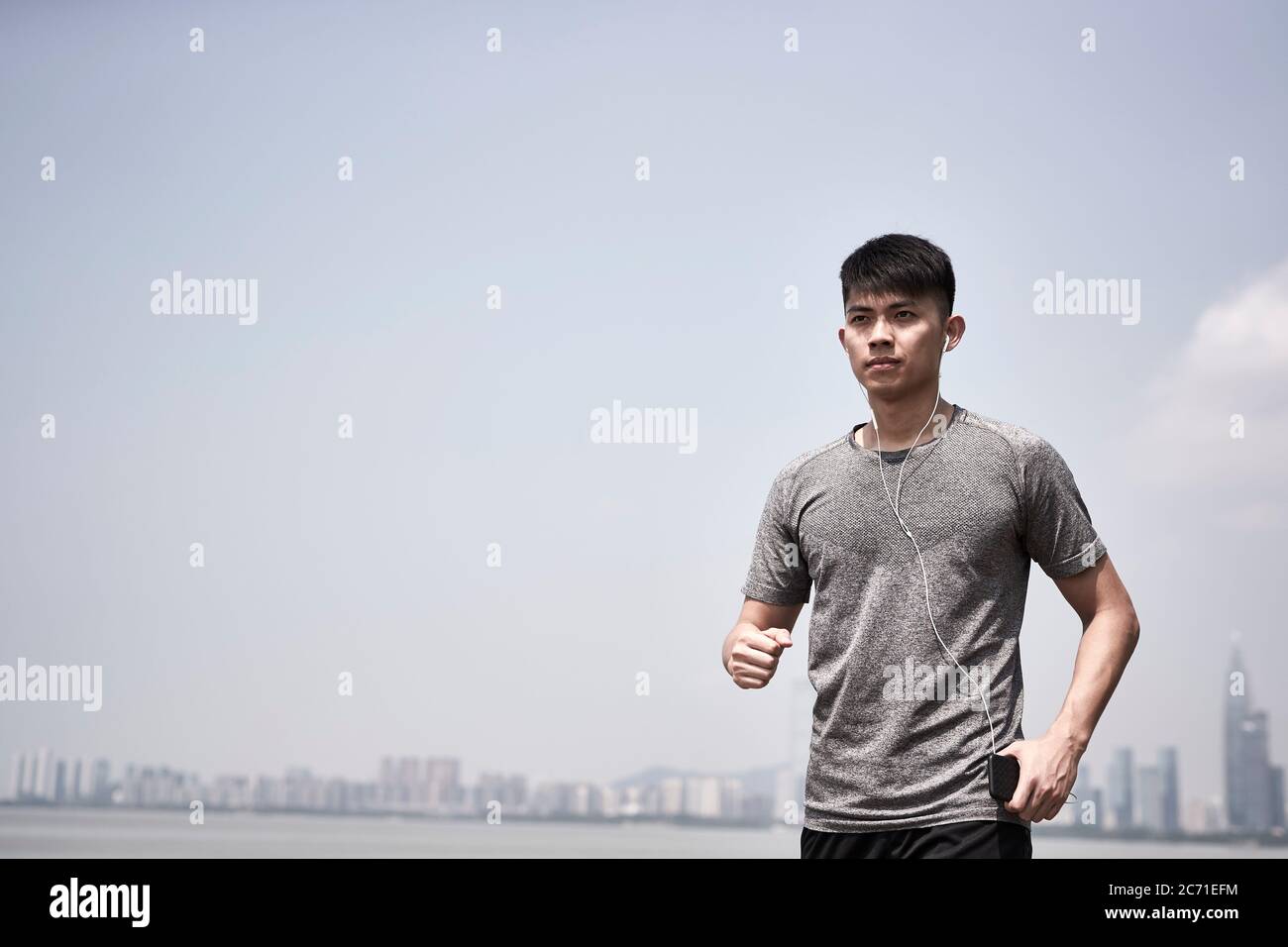 giovane adulto asiatico pronto a correre all'aperto in riva al mare Foto Stock