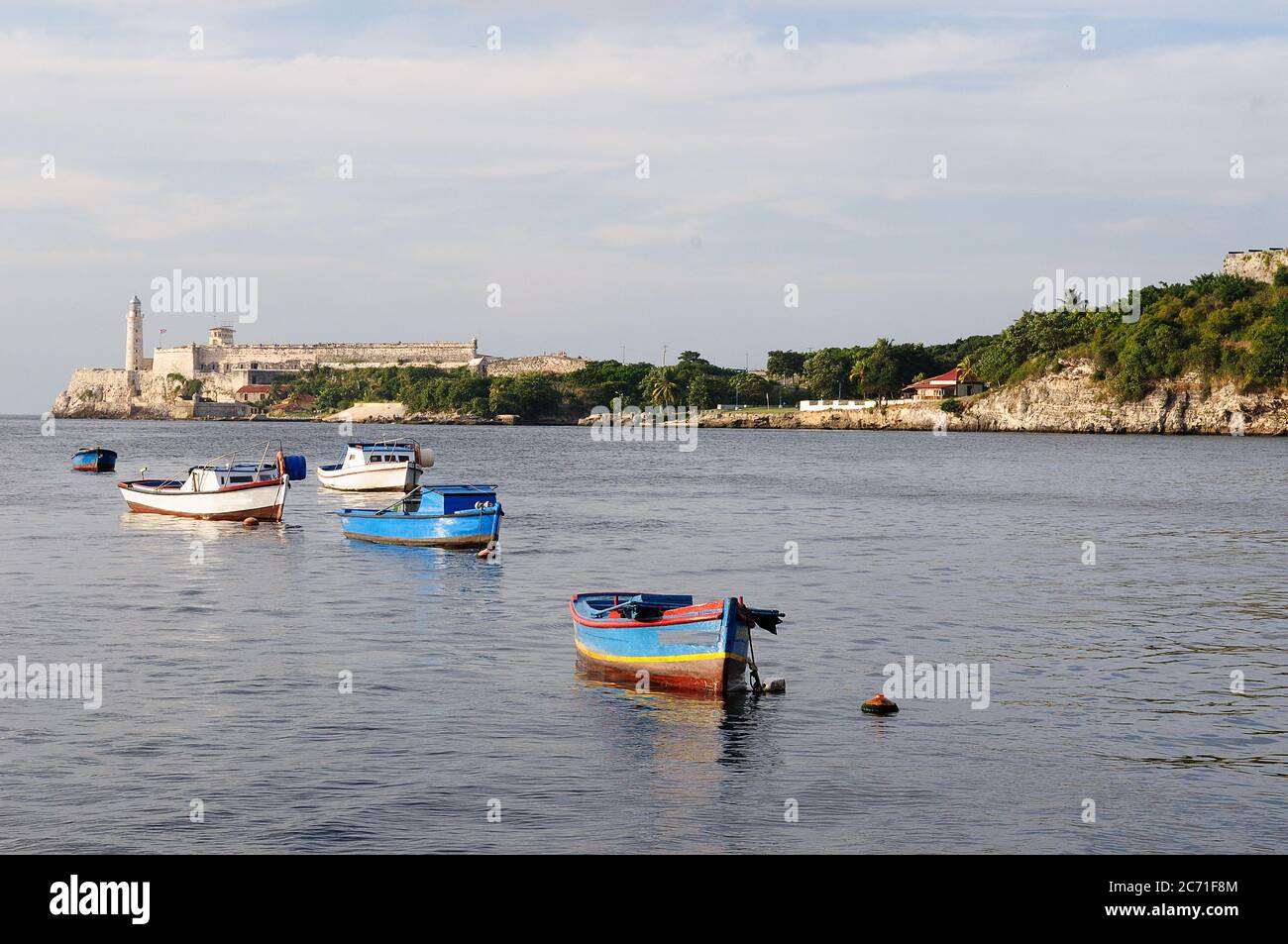 Vista su una barca da pesca rustica alla baia di l'avana al tramonto, faro di morro all'Avana Foto Stock