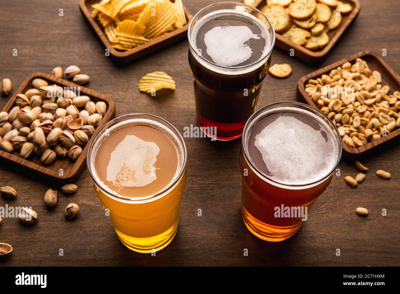Festa della birra nel pub. Vari di birra, cracker, arachidi, pistacchi e patatine in piatti e spruzzati sul tavolo Foto Stock