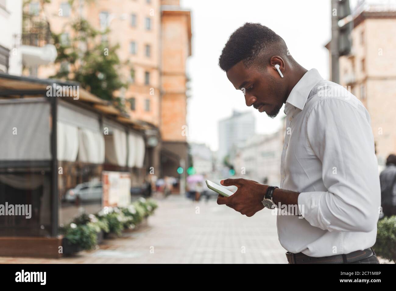 Ritratto esterno di giovane moderno africano nero con cellulare in strada. Foto Stock