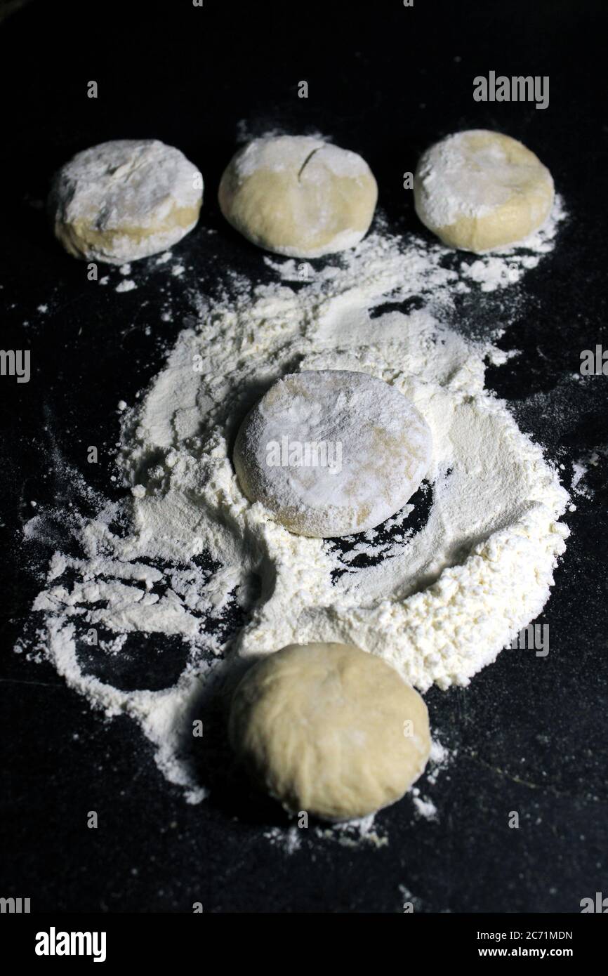 Pezzo di impasto di lievito con farina di grano su fondo nero. Pane non cotto per la preparazione di Roti o Chapati (pane piatto indiano). Foto Stock