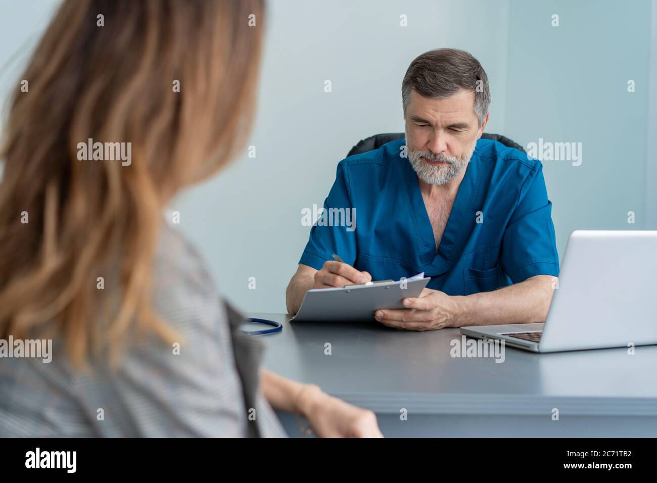 Il chirurgo senior consulta la giovane donna, il medico con paziente in ufficio medico. Foto Stock