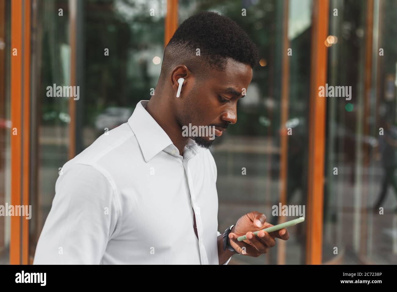Ritratto esterno di giovane moderno africano nero con cellulare in strada. Foto Stock