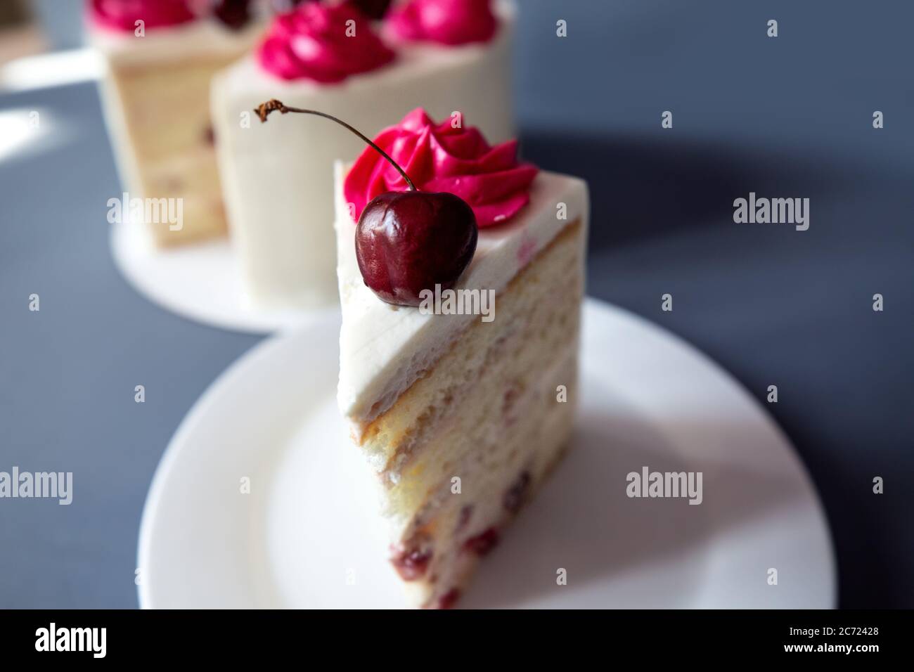 Innaffiatura in bocca cheesecake alla ciliegia macro con forchetta. Girato su backgrond blu Foto Stock