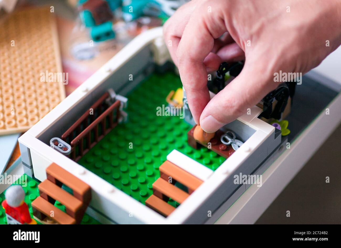 Tambov, Federazione Russa - 20 Giugno 2020 primo piano di persona a mano che fa interno della casa Lego sul tavolo con le istruzioni. Profondità di campo poco profonda Foto Stock